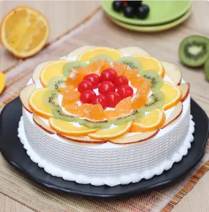 Fruits Cake from the best bakery cakes shop in Aligarh, fresh fruit cake topped with sliced oranges, kiwi, cherries, and smooth cream frosting